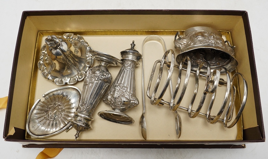 Sundry silver including a pair of Edwardian pepperettes, a five bar toast rack, a mustard pot (a.f.), a pair of sugar tongs and a cover. Condition - poor to fair
